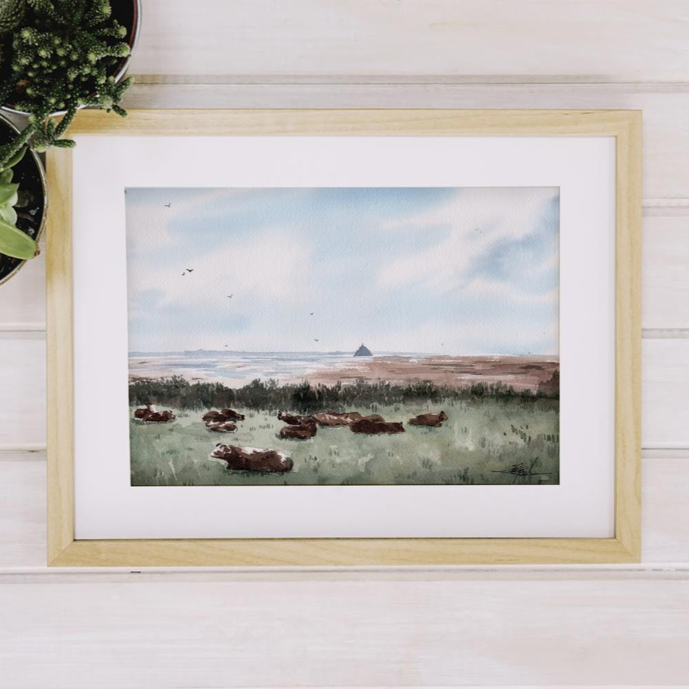 Reproduction encadrée d'une aquarelle de la Pointe du Grouin du Sud, avec des vaches en premier plan, réalisée par l'artiste normande Emma de Morel.