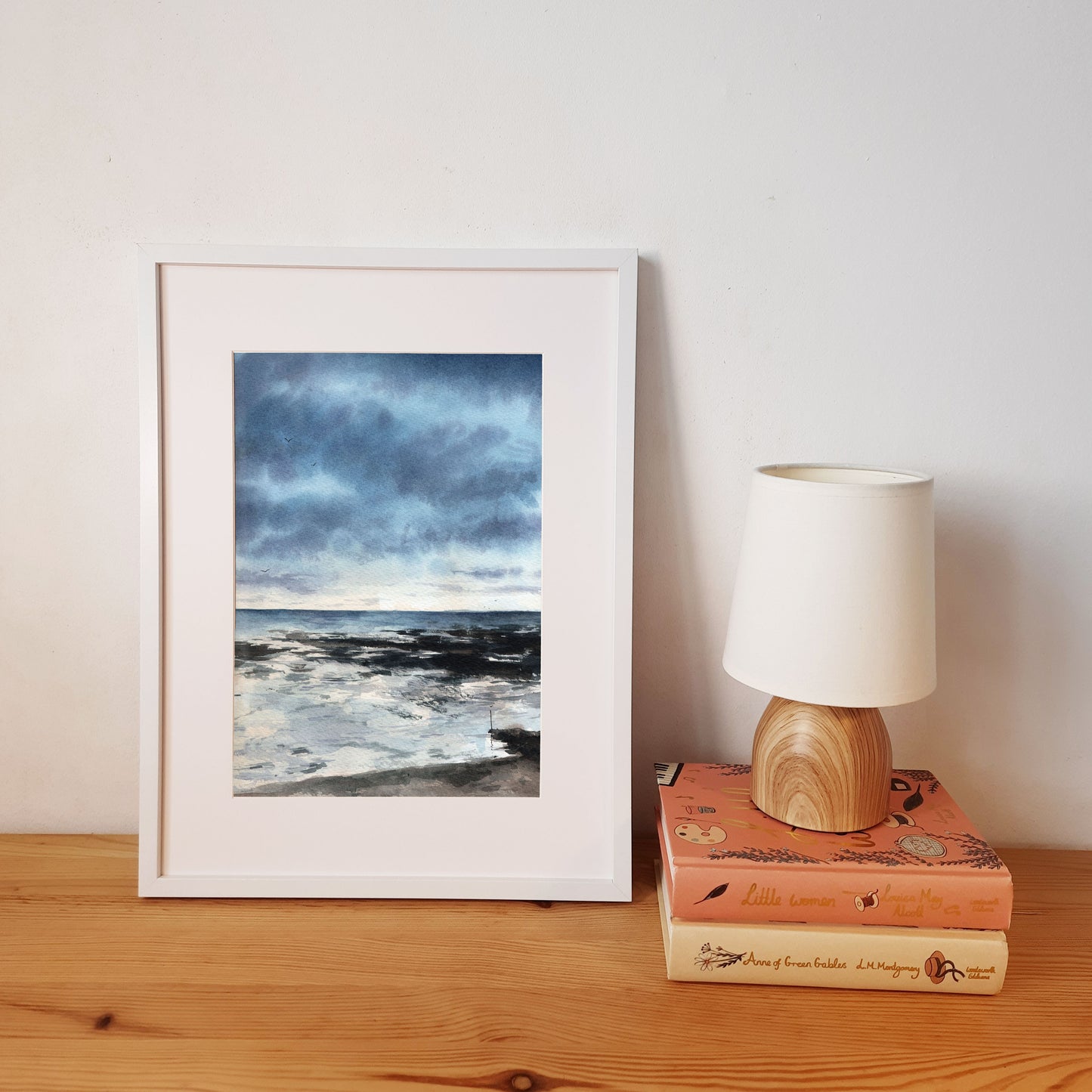 Reproduction A4 encadrée format portrait d'une aquarelle d'un paysage normand avec des nuages bleu profond et la mer au loin.
