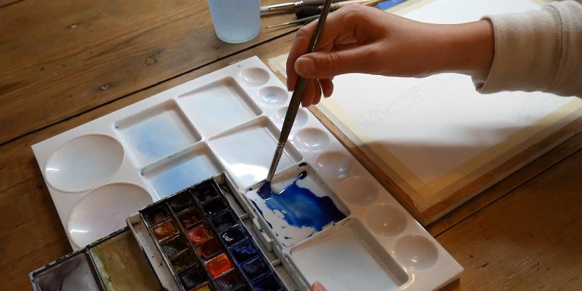 Emma de Morel artiste aquarelliste mélange ses couleurs pour peindre une aquarelle.